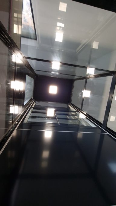 Blick nach oben in einen modernen, lichtdurchfluteten Aufzugschacht.